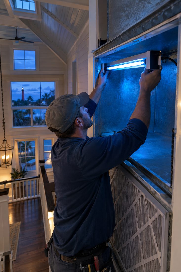 A UV light being installed in a return plenum inside a two-story Old Florida style home with a tin roof near the lighthouse area in Jupiter, FL